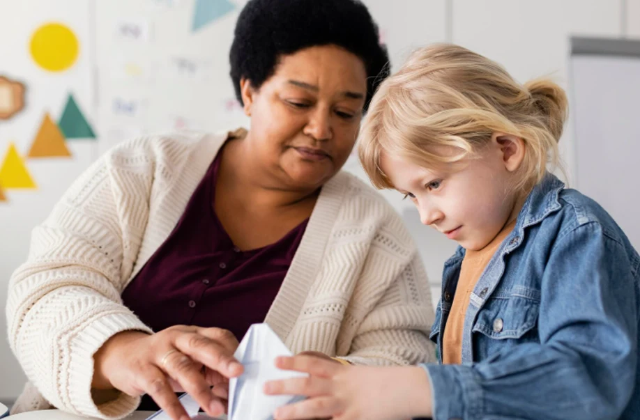 A social worker does arts and crafts with a child in child care