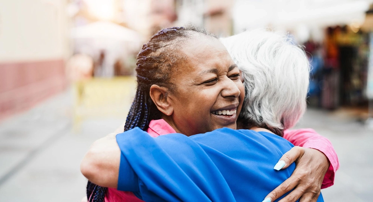 A female community worker hugging an elderly lady
