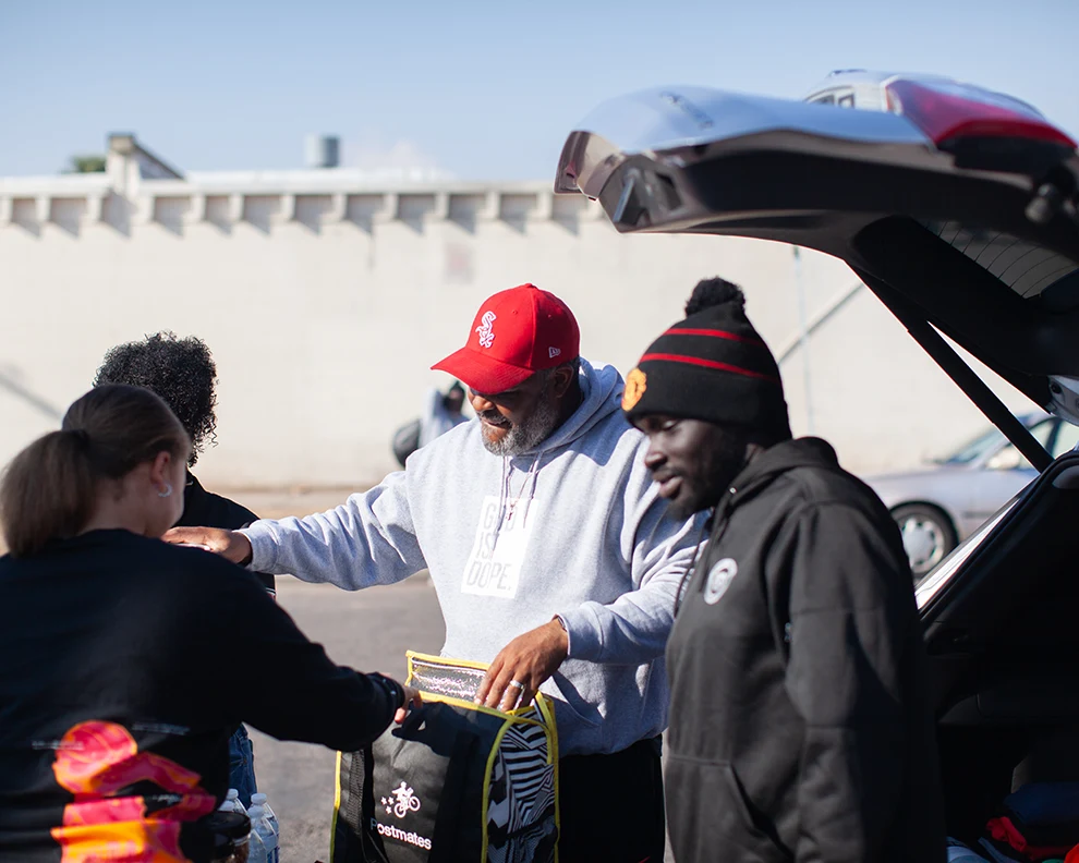 Unhoused people waiting in line to receive a food giveaway bag given out by Ruthie's Cliff