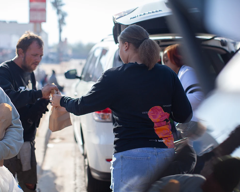 A member of Ruthie's Cliff is handing out bags filled with donated items to a homeless person