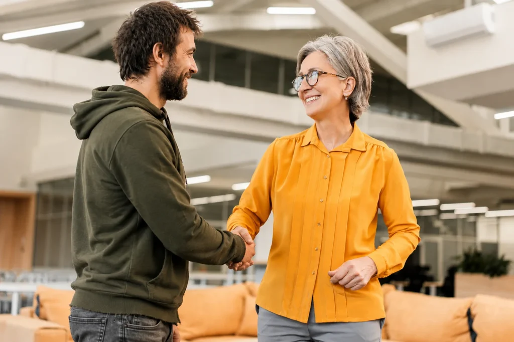 A female social worker is shaking a job seeker's hand inside of an office