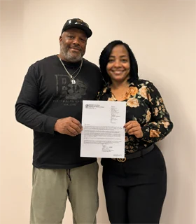 The founder of Ruthie's Cliff is holding and showing the official 503 (c)(3) status document together with her husband