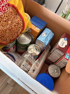 Top view into a cardboard box filled with donated non-perishable food items