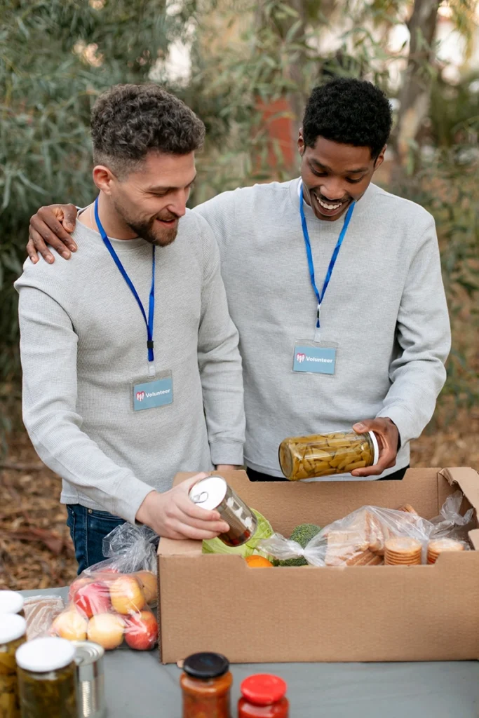Two young volunteers enjoying packaging food boxes for a charity event