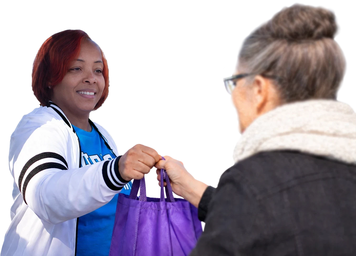 The founder of the non-profit Ruthie's Cliff is handing an older lady a bag of free charity items